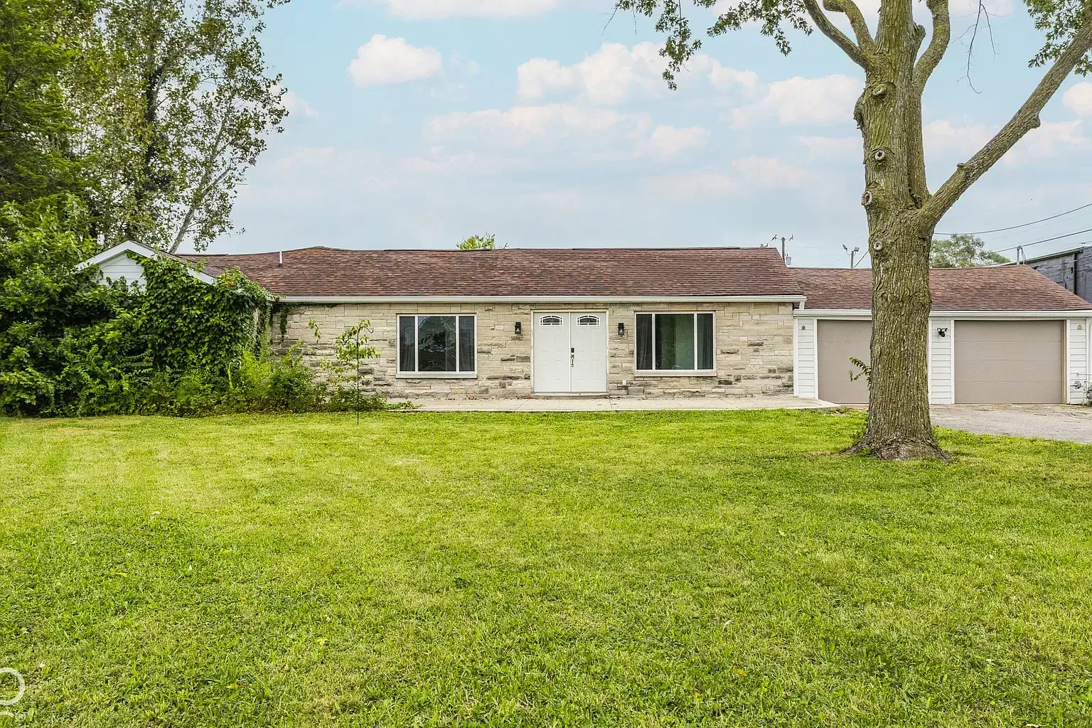 530 E Sumner Ave, a single story ranch with a tan stone front, white double front doors, an attached two car garage, and a large front lawn with a mature tree