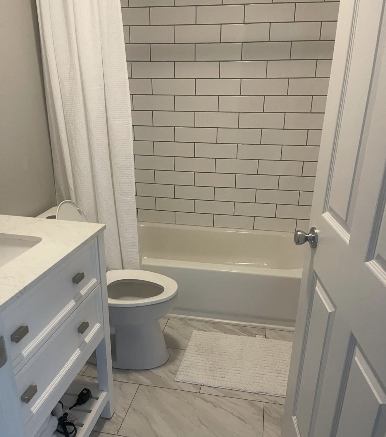 Bright bathroom with white subway tile surround, a soaking tub, and a marble look floor