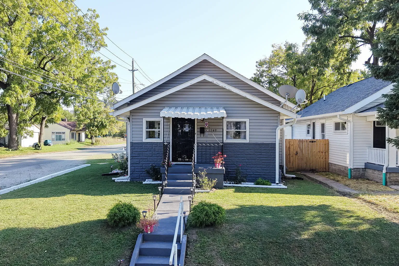 1549 E Legrande Ave, a single story bungalow with light gray siding, a charcoal stone front, white trim, and a scalloped awning over the front steps